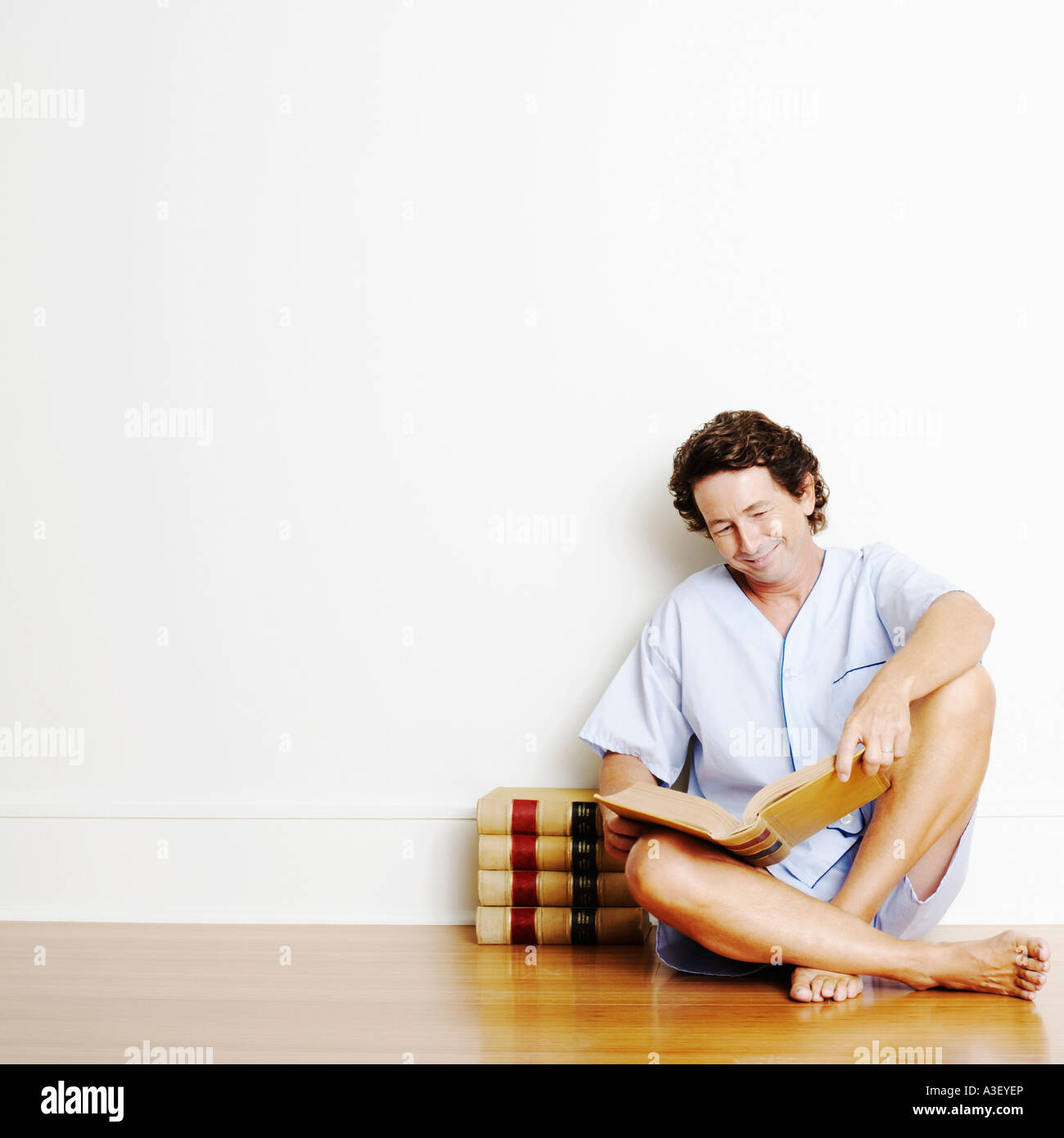 Mature man sitting on the floor and reading a book Stock Photo - Alamy