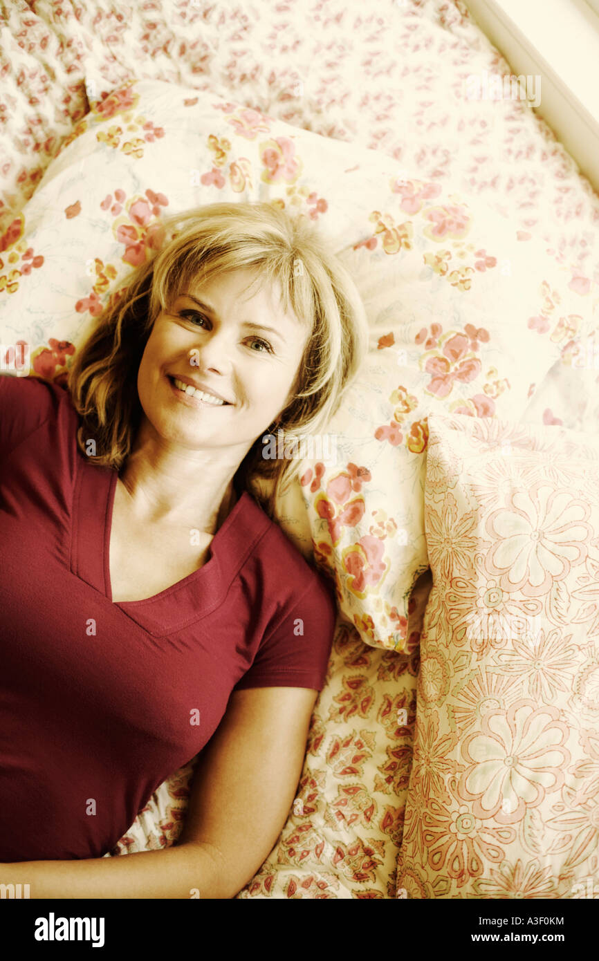 Portrait of a mature woman lying on the bed and smiling Stock Photo - Alamy
