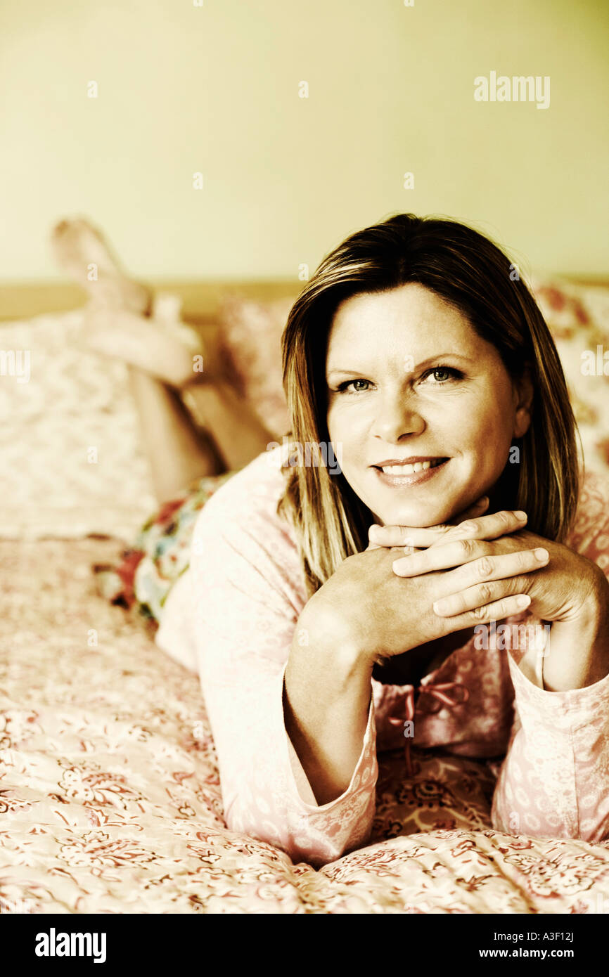 Portrait of a mature woman lying on the bed and smiling Stock Photo - Alamy