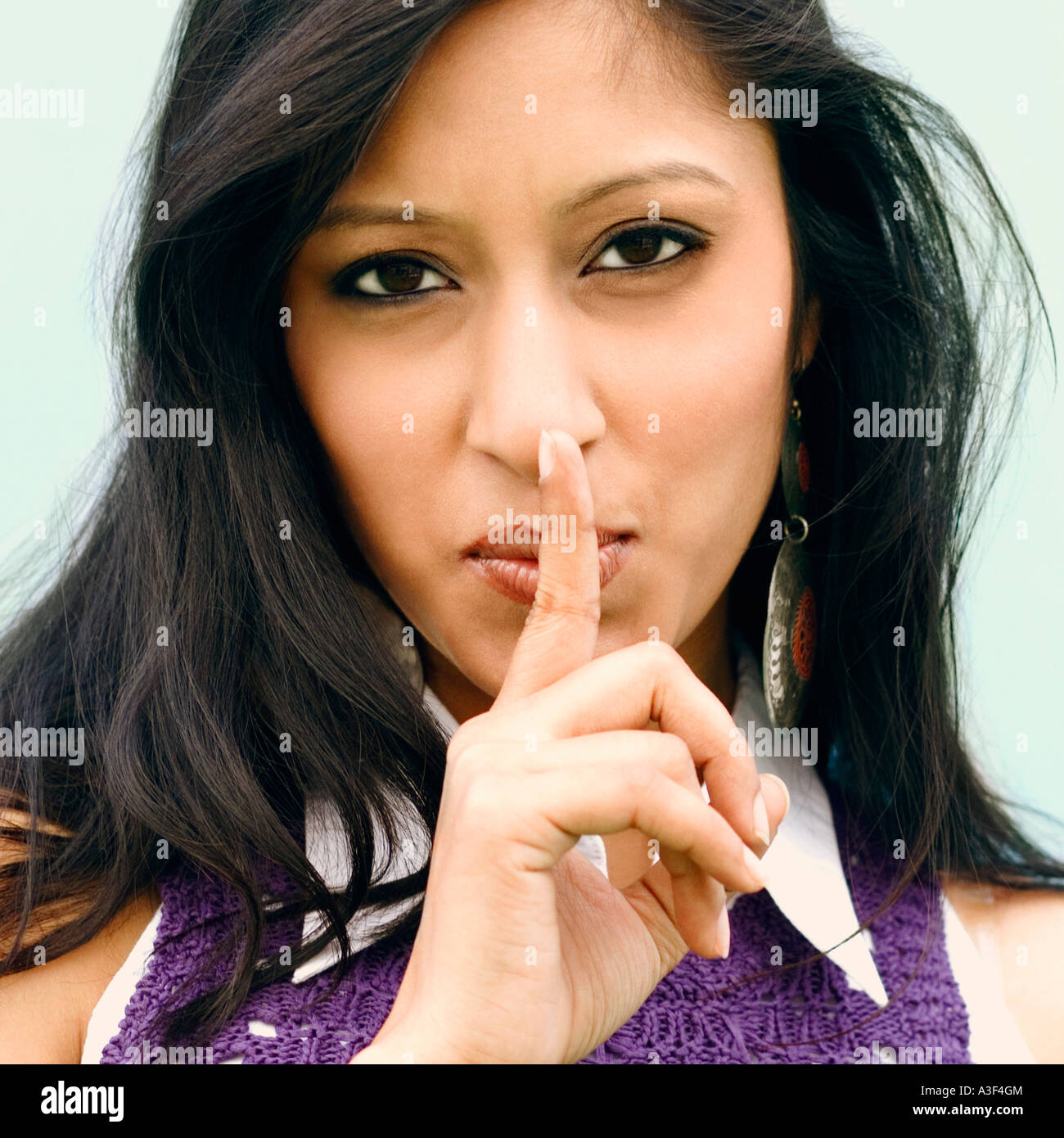 Portrait of a young woman with her finger on her lips Stock Photo - Alamy