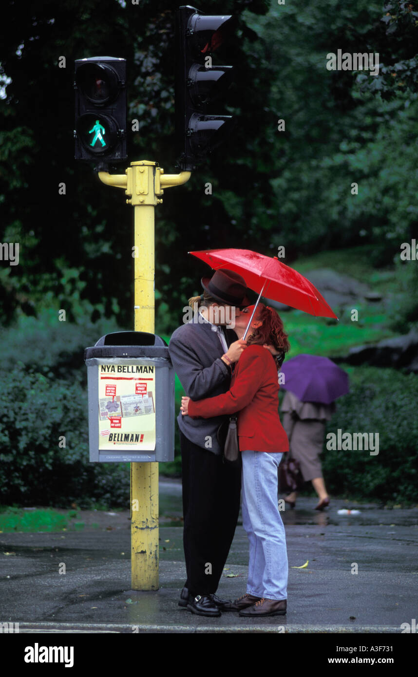 Couple kissing under red umbrella on rainy day in Stockholm Sweden