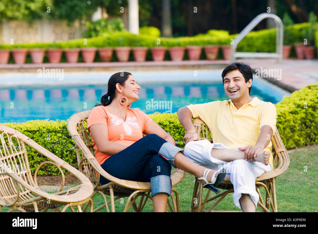 Young couple sitting on a chair at the poolside and smiling Stock Photo