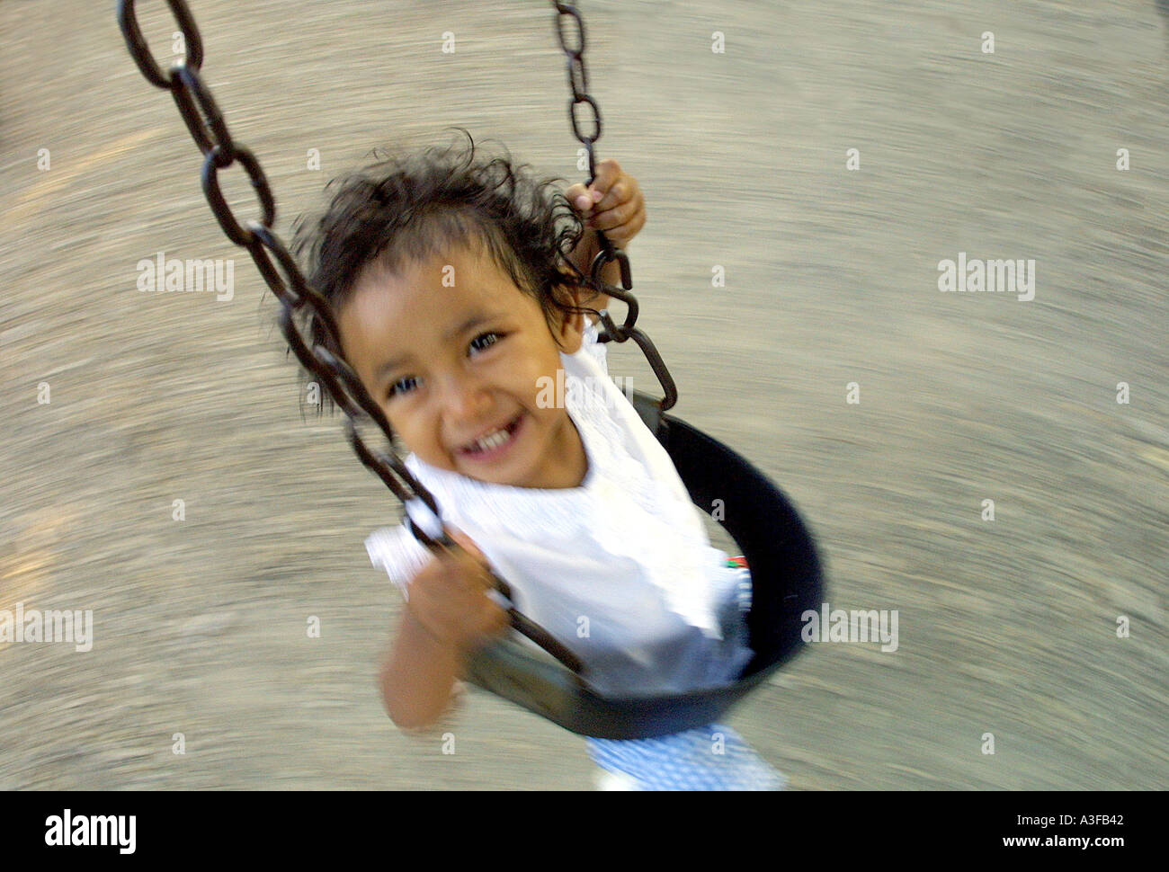 18 month old girl smiles and swings in a blur Stock Photo