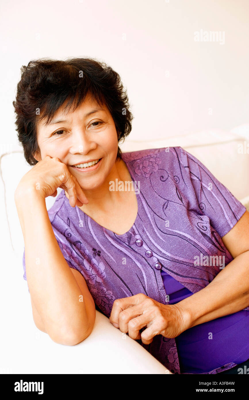 Portrait of a mature woman sitting on a couch Stock Photo - Alamy