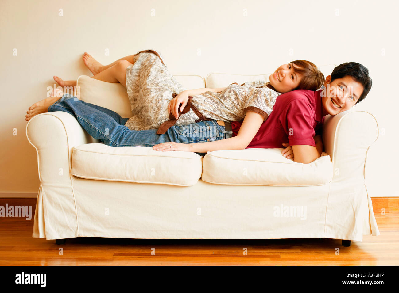 Portrait of a young couple lying back to back on a couch Stock Photo