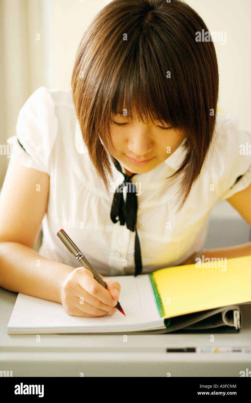 Close-up of a young woman writing on a notepad in a classroom Stock Photo