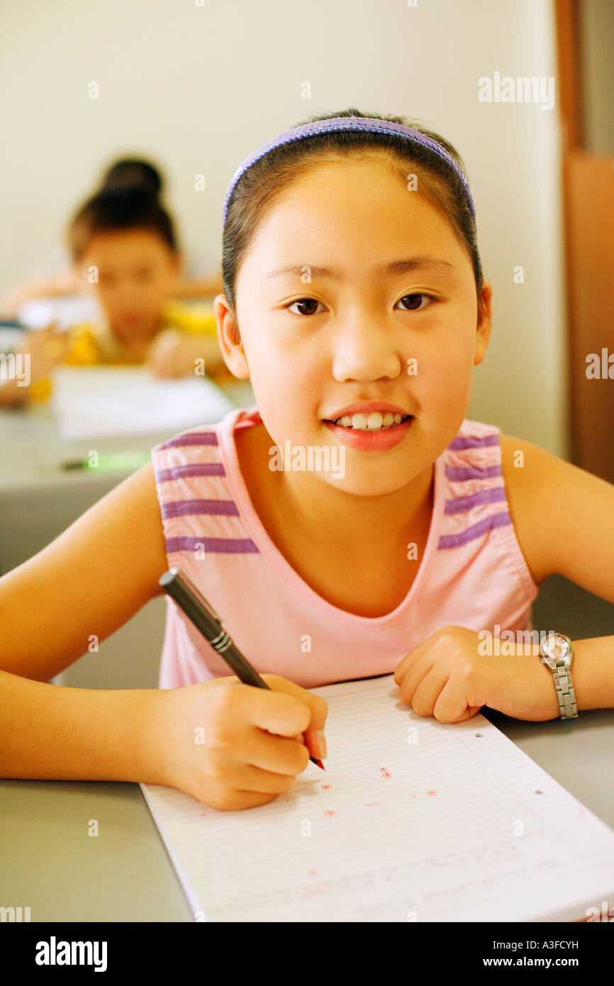 Portrait of a girl holding a pen on a notepad in the classroom Stock ...