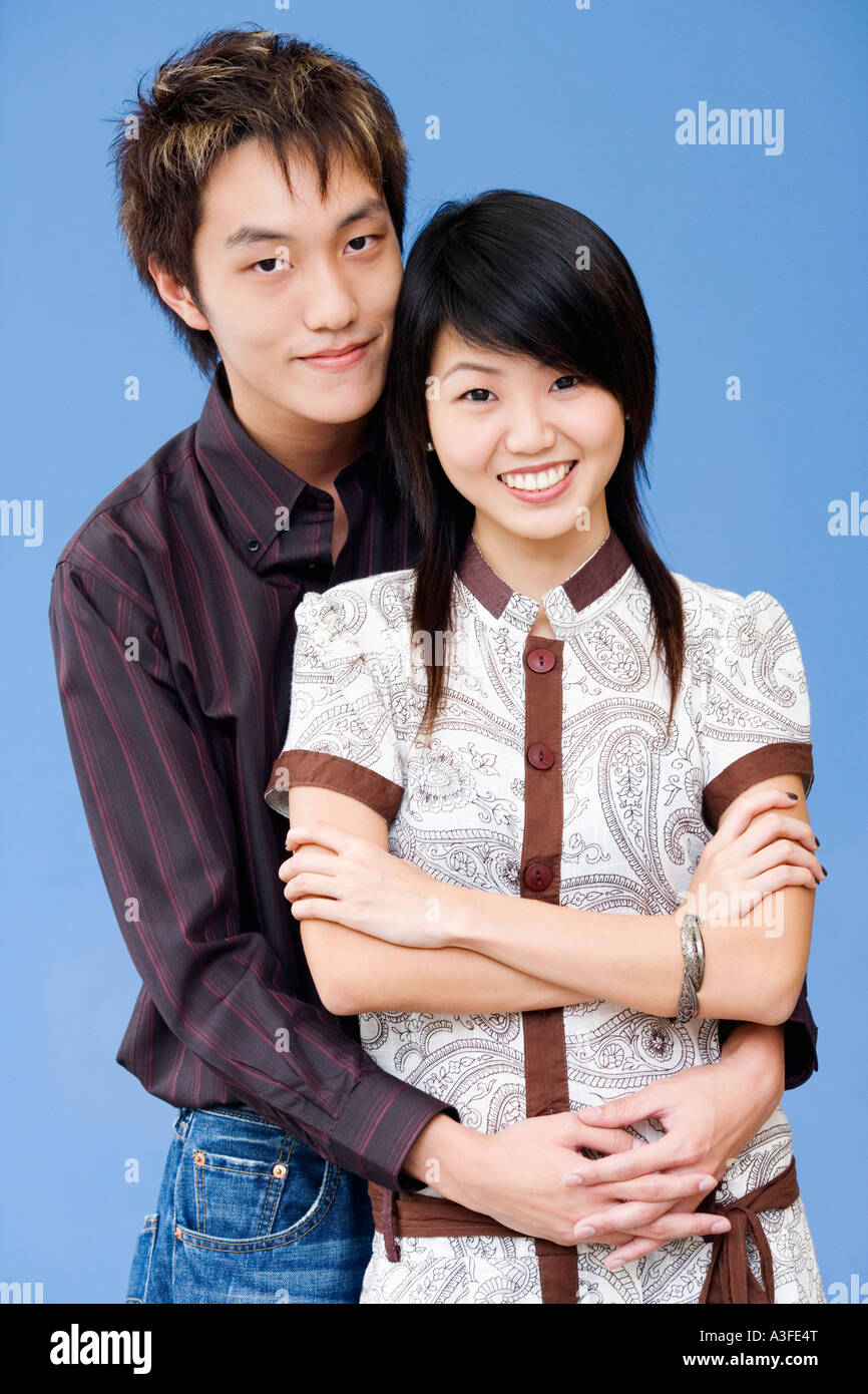 Portrait of a young man embracing a young woman from behind Stock Photo ...