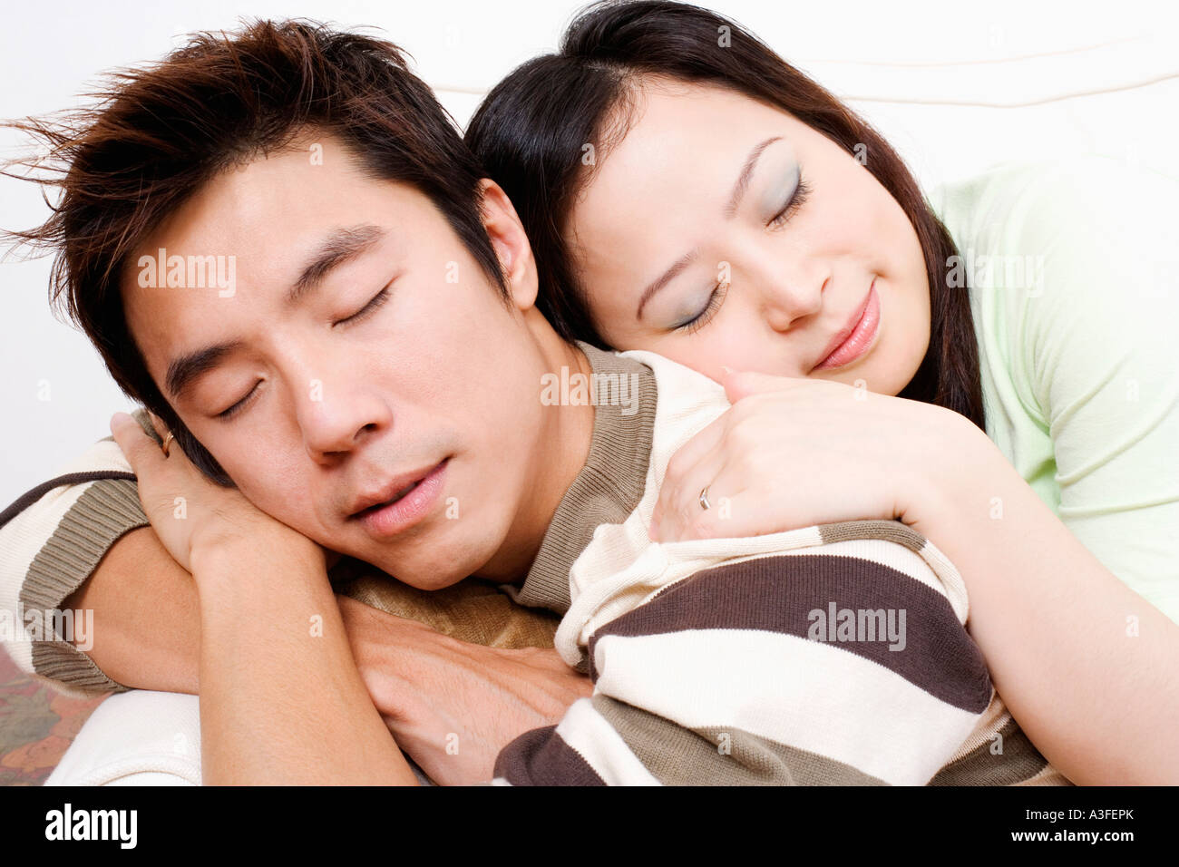 Close-up of a mid adult man and a young woman sleeping on a couch Stock ...