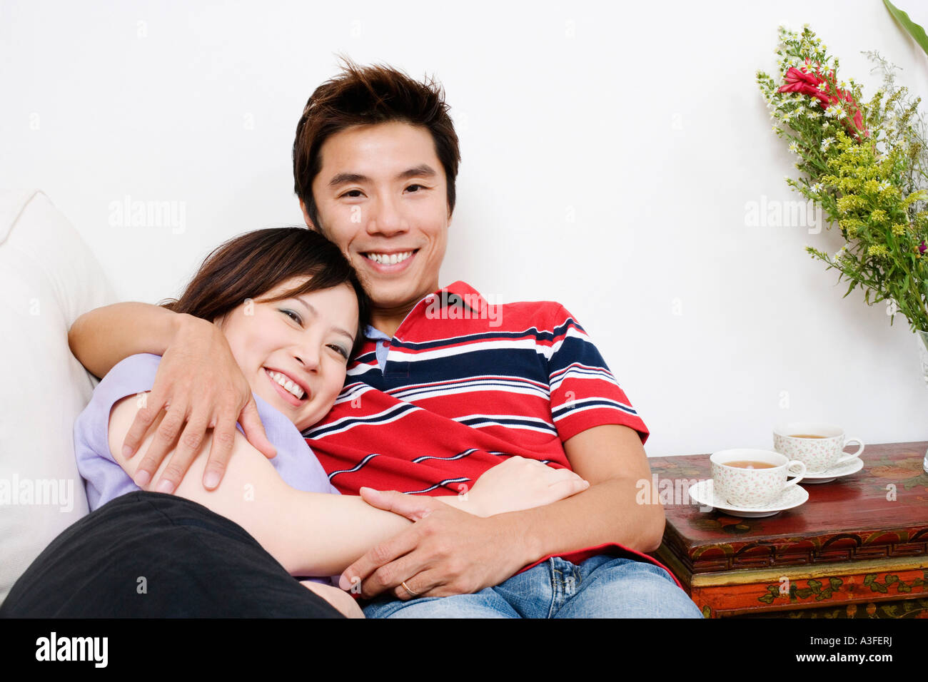 Portrait of a mid adult man lying on a couch with a young woman and ...