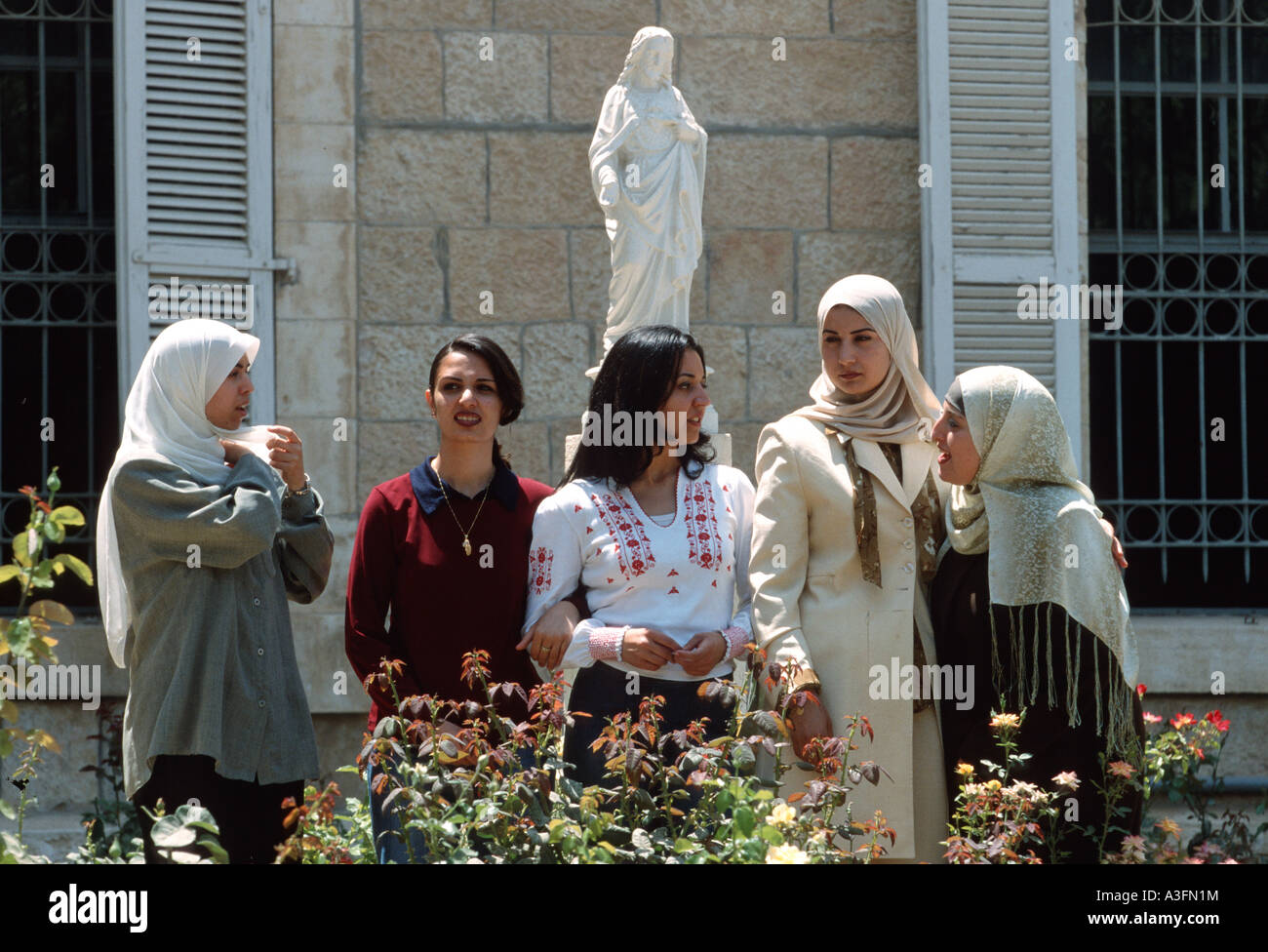 Muslim students in front of a Statue of Jesus Christ, Catholic University of Bethlehem, Palestine Stock Photo