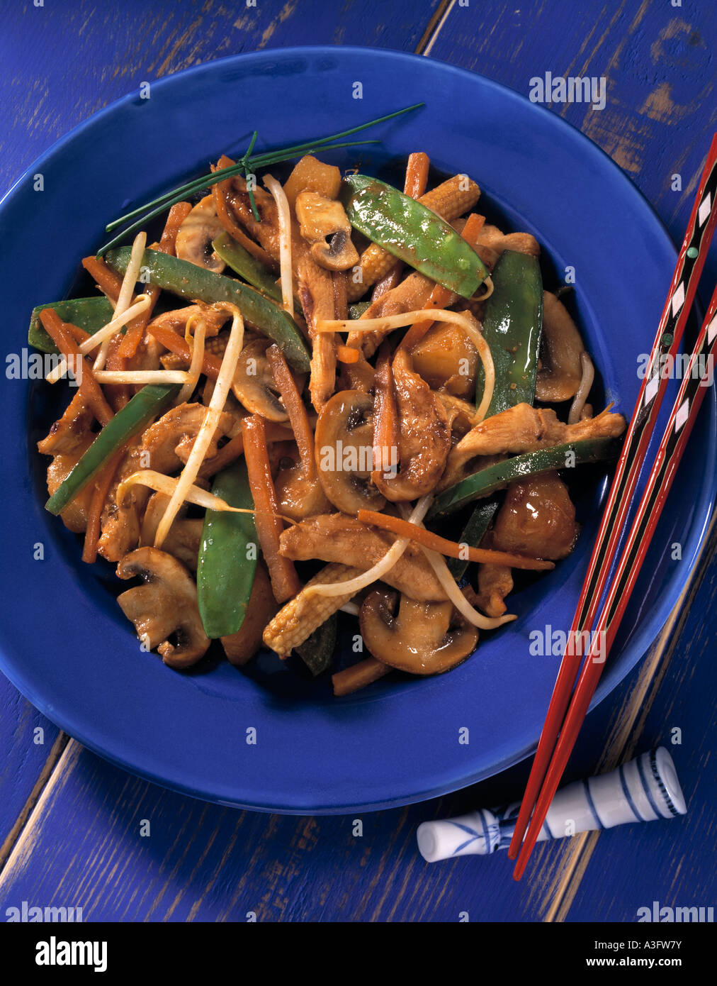 Overhead shot of a chicken stir fry on a blue plate with chopsticks editorial food Stock Photo