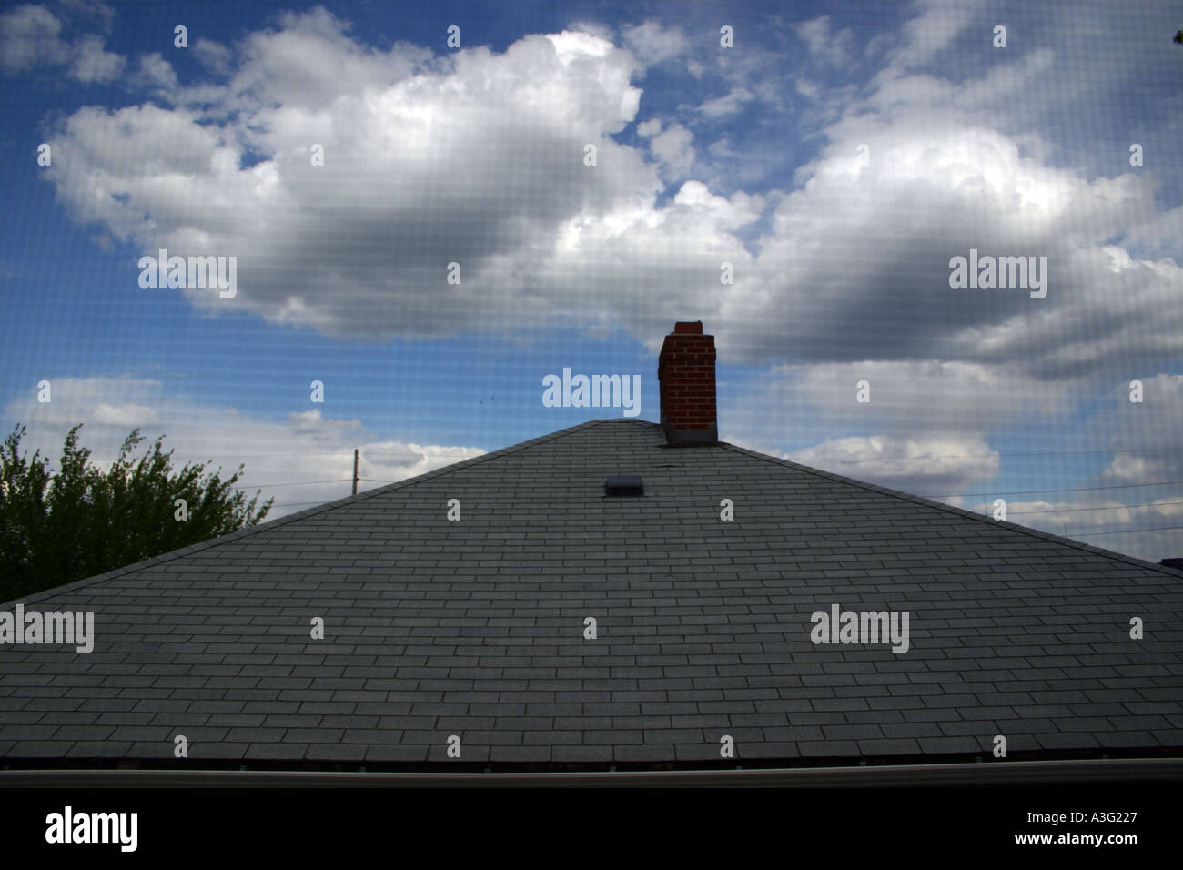view of roof and cloudy blue sky through the screen in rooftop roof top window Stock Photo