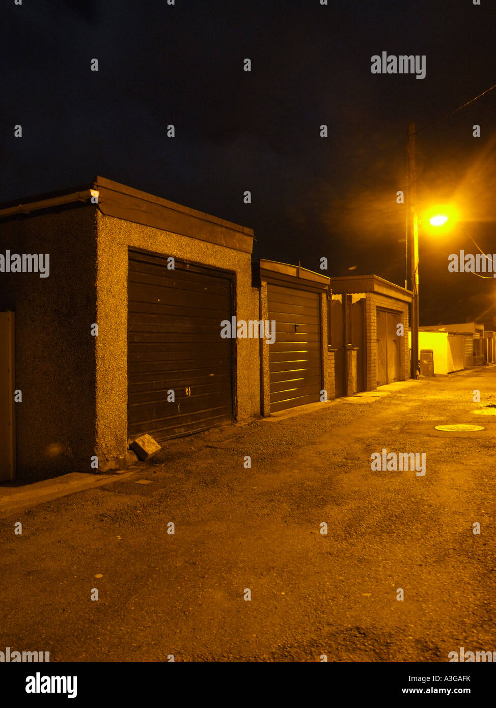 a row of closed residential garages in back alley way at night Stock