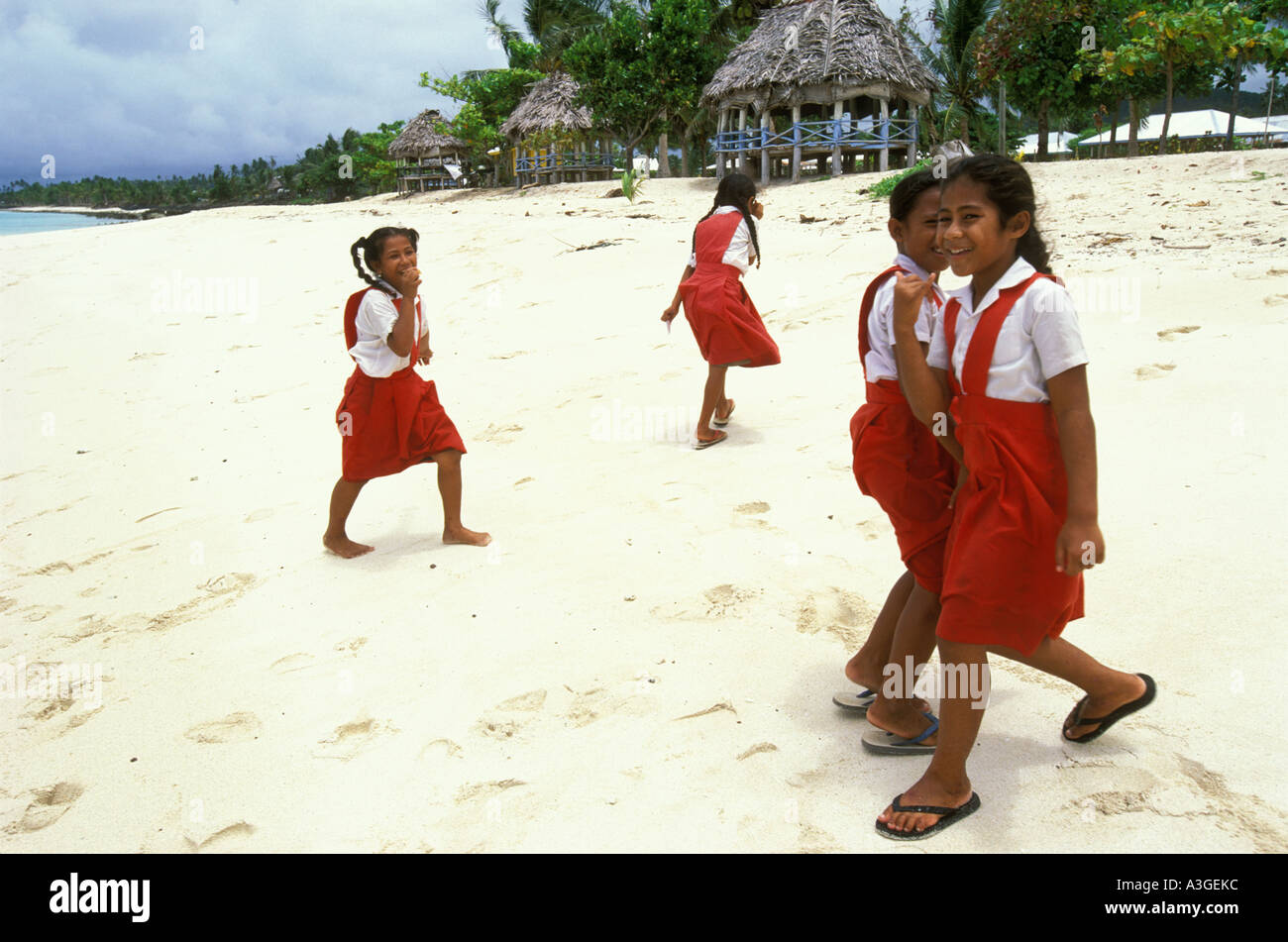 Girls in school uniform in front of some beach fales at Faga Beach