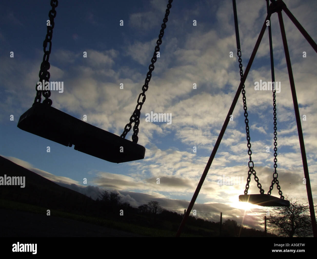 two swings in play ground against dramatic moody sky Stock Photo Alamy