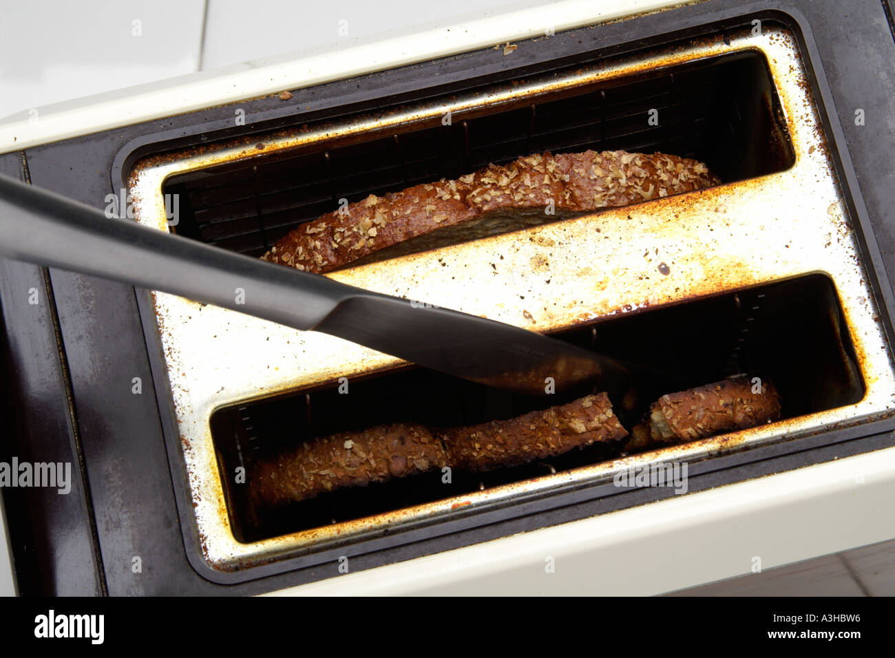 knife in well used toaster trying to remove stuck piece of bread Stock