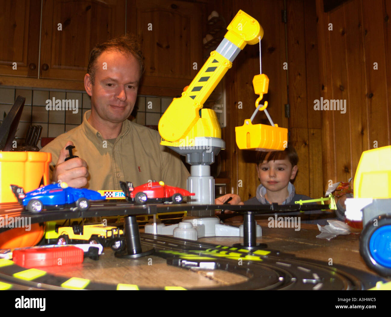 Man playing with child's toy, as young boy looks on. Never Growing Up! Stock Photo