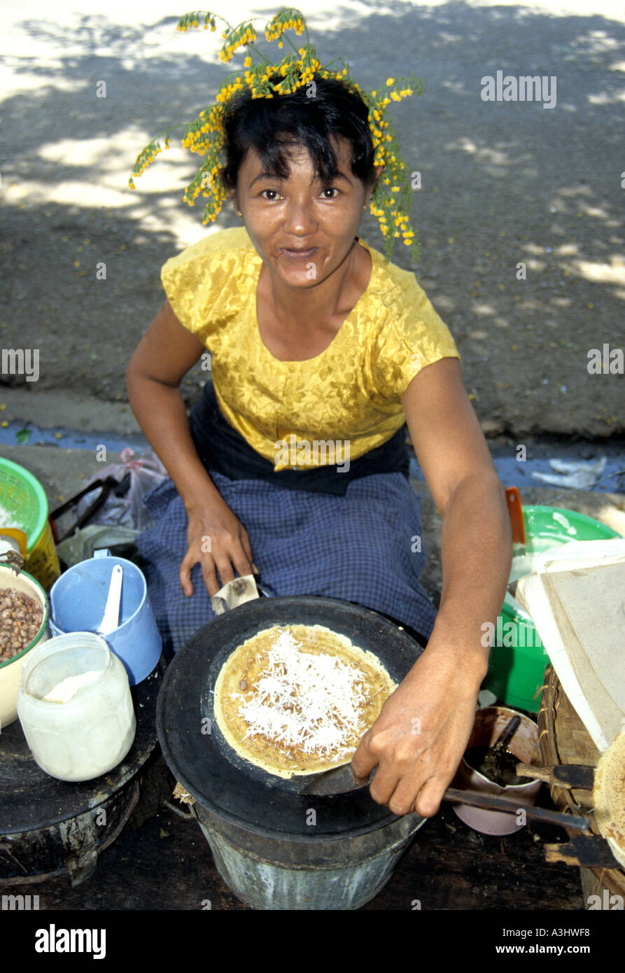 market stall woman with flowers in her hair,offers food to home going workers at the ferry pier in Yangon ,Burma Stock Photo