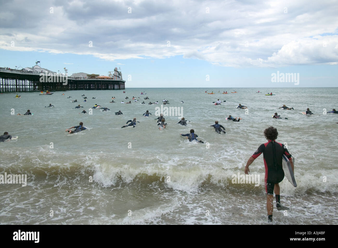 Surfers swimming in the sea next to the Palace Pier Brighton at the Surfers Against Sewage SAS protest Stock Photo