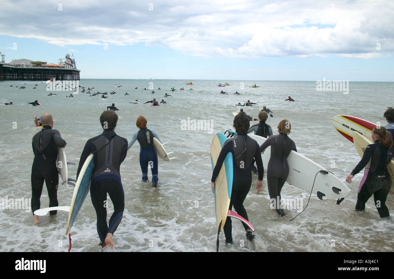 Surfers enter the sea next to the Palace Pier Brighton at the Surfers Against Sewage SAS protest Stock Photo