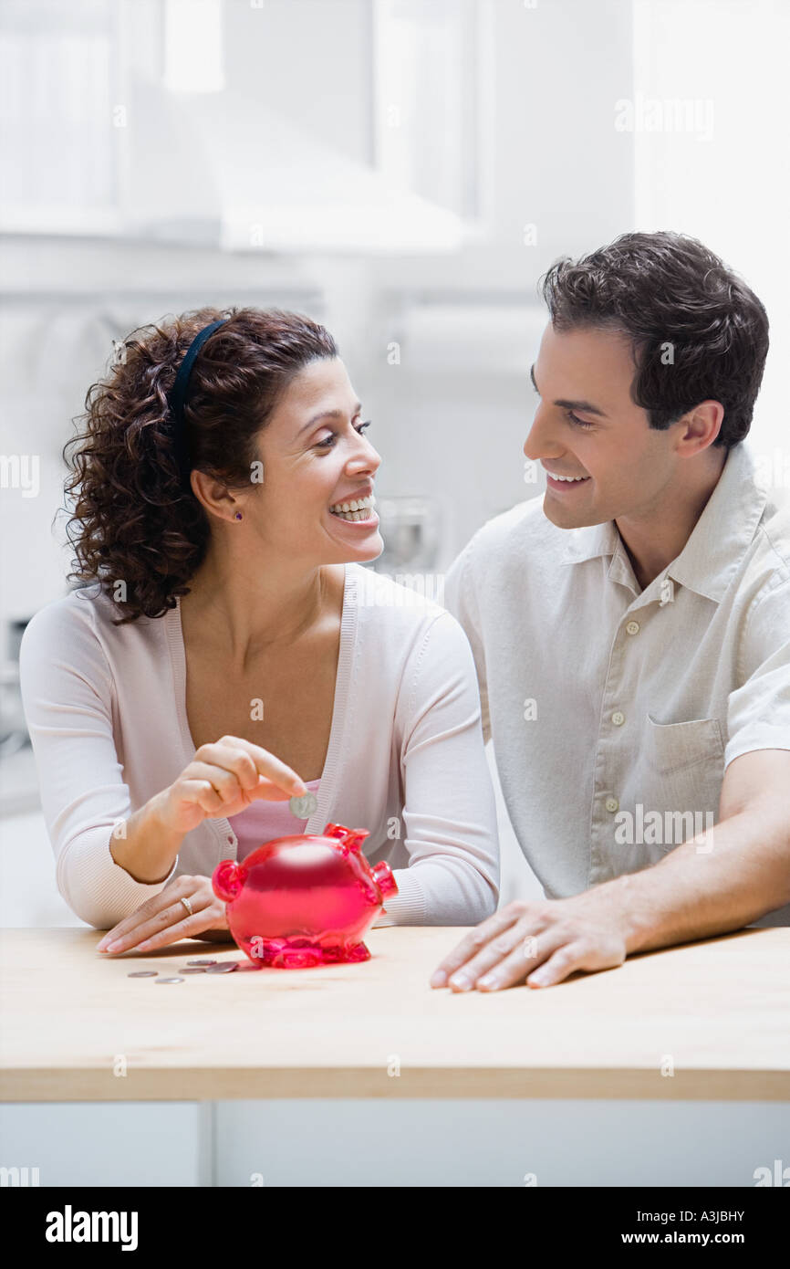 Couple placing a coin in piggy bank Stock Photo - Alamy