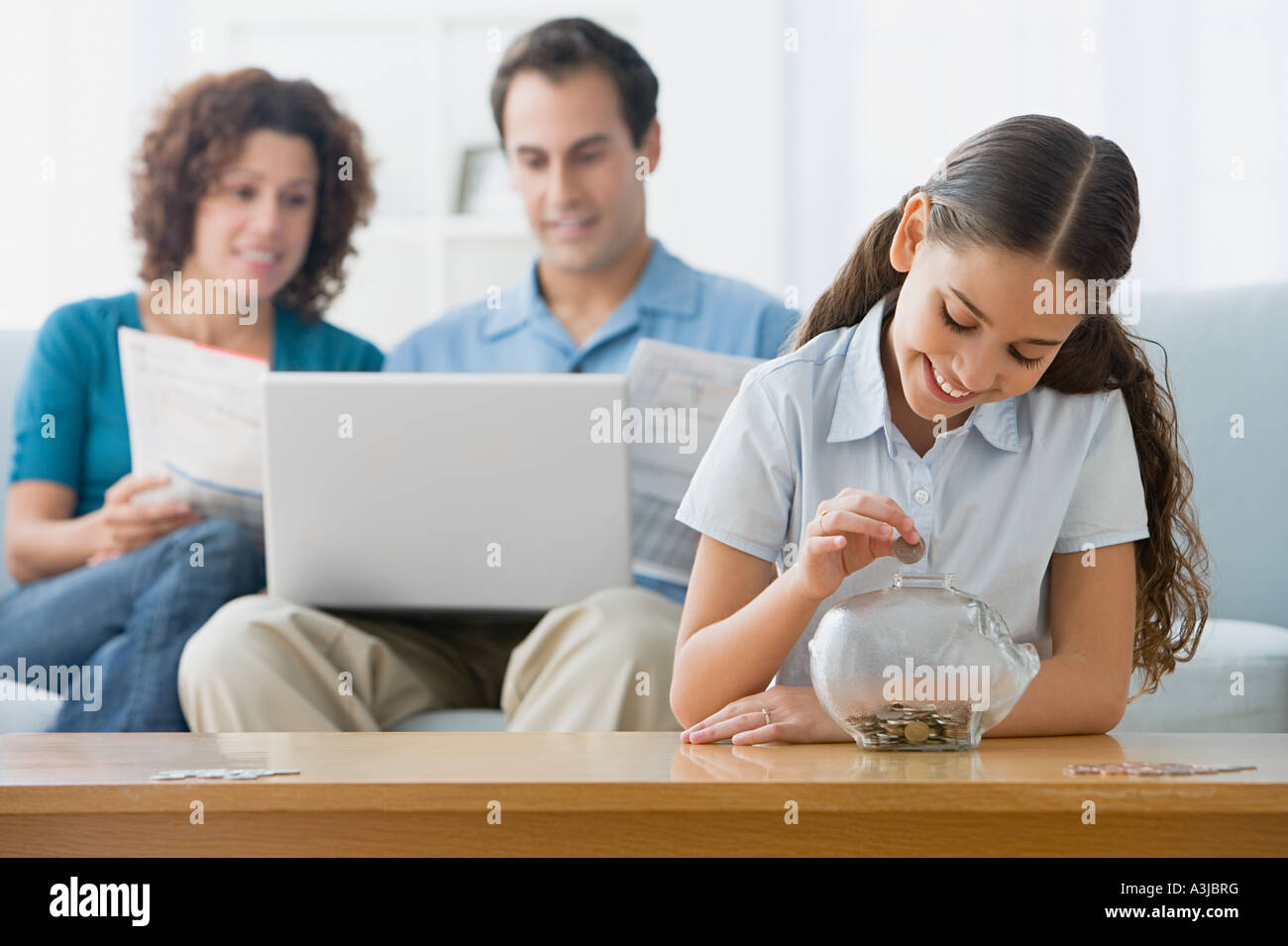 Girl putting coins in a piggy bank Stock Photo - Alamy