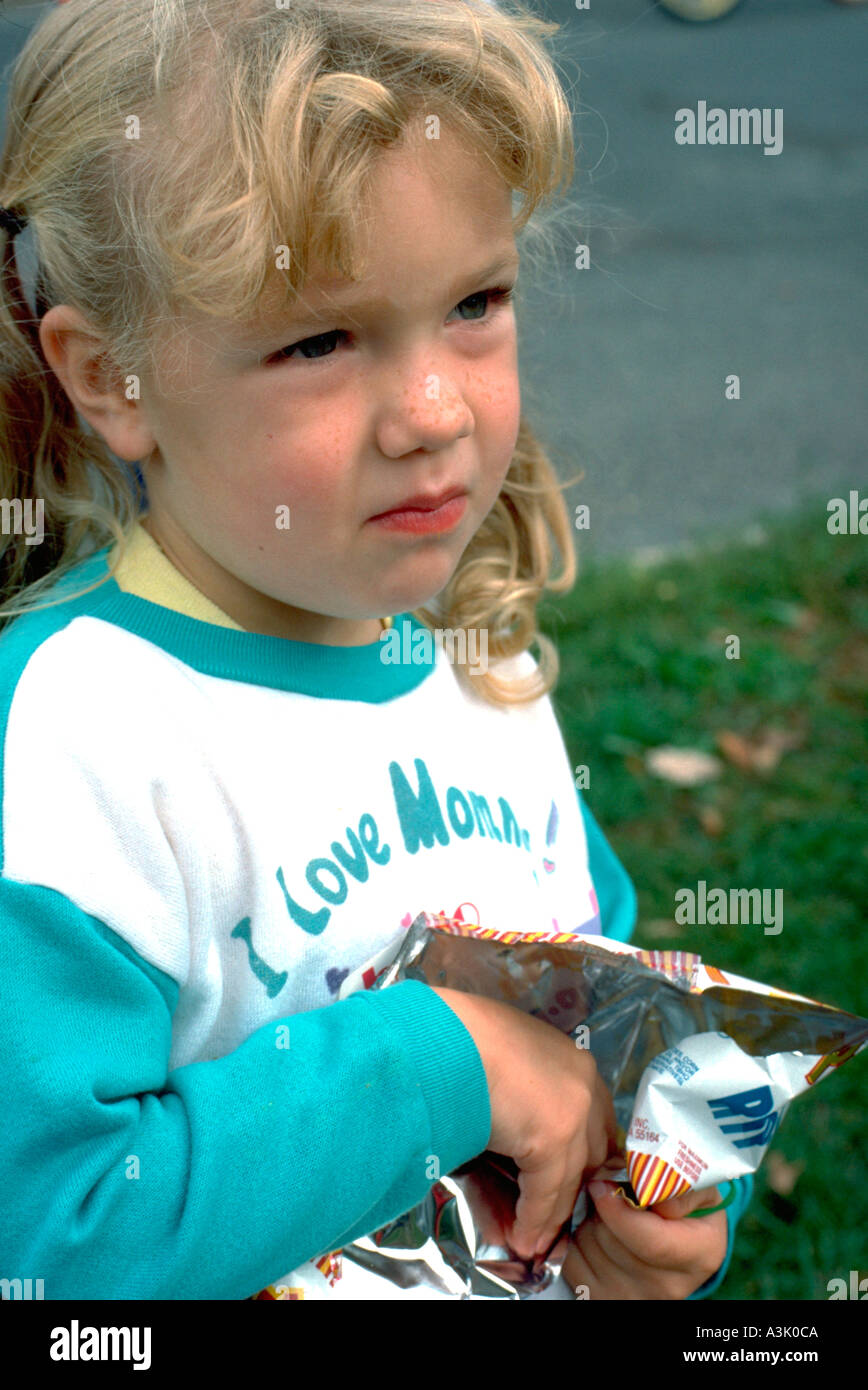 Girl eating potato chips at Catholic School bike-a-thon age 3. St Paul Minnesota USA Stock Photo