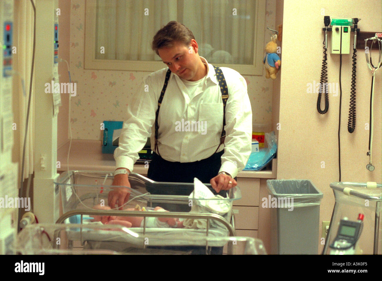 Father enjoying a moment with newborn son in hospital nursery age 30
