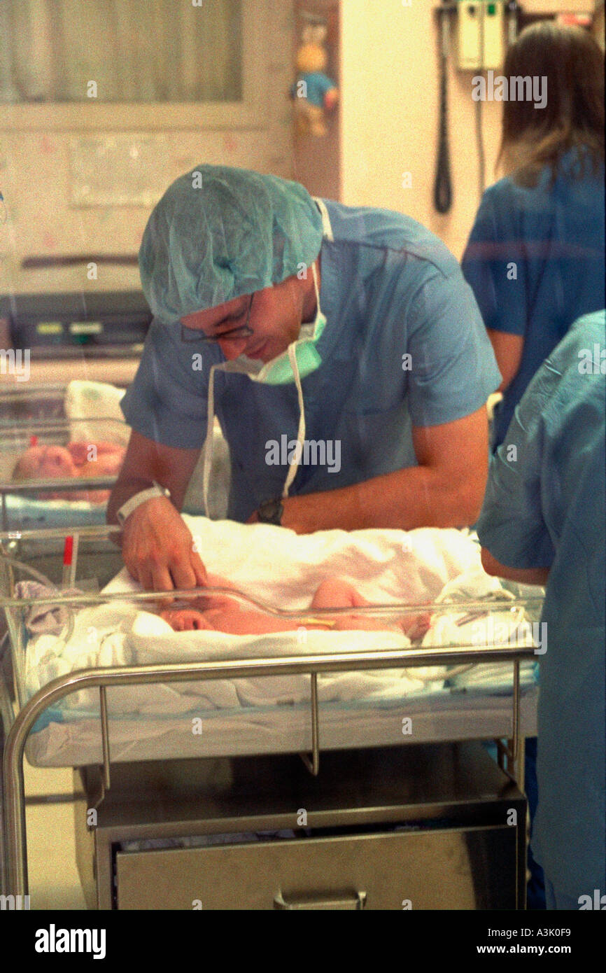 Doctor age 35 examining newborn baby boy in hospital nursery. Edina
