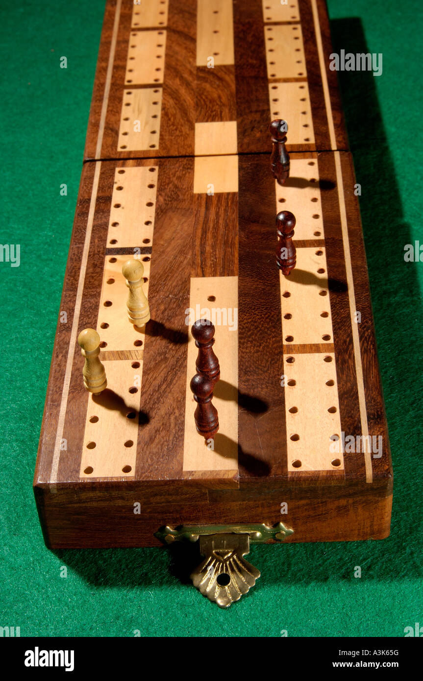 Traditional wooden cribbage board with wooden shaped pegs standing on green baize card table Stock Photo