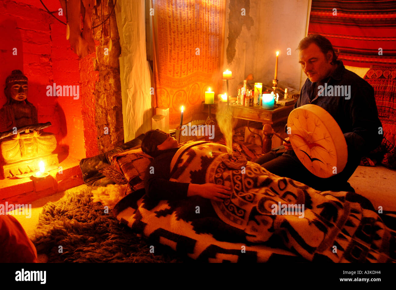 Shaman and healer treating a patient in therapy session by candlelight. Stock Photo