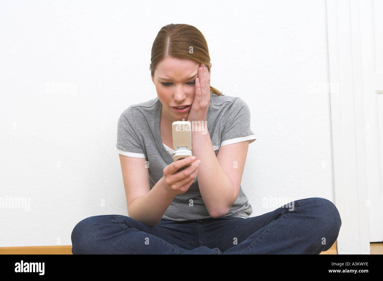 young woman receiving shocking text message Stock Photo - Alamy