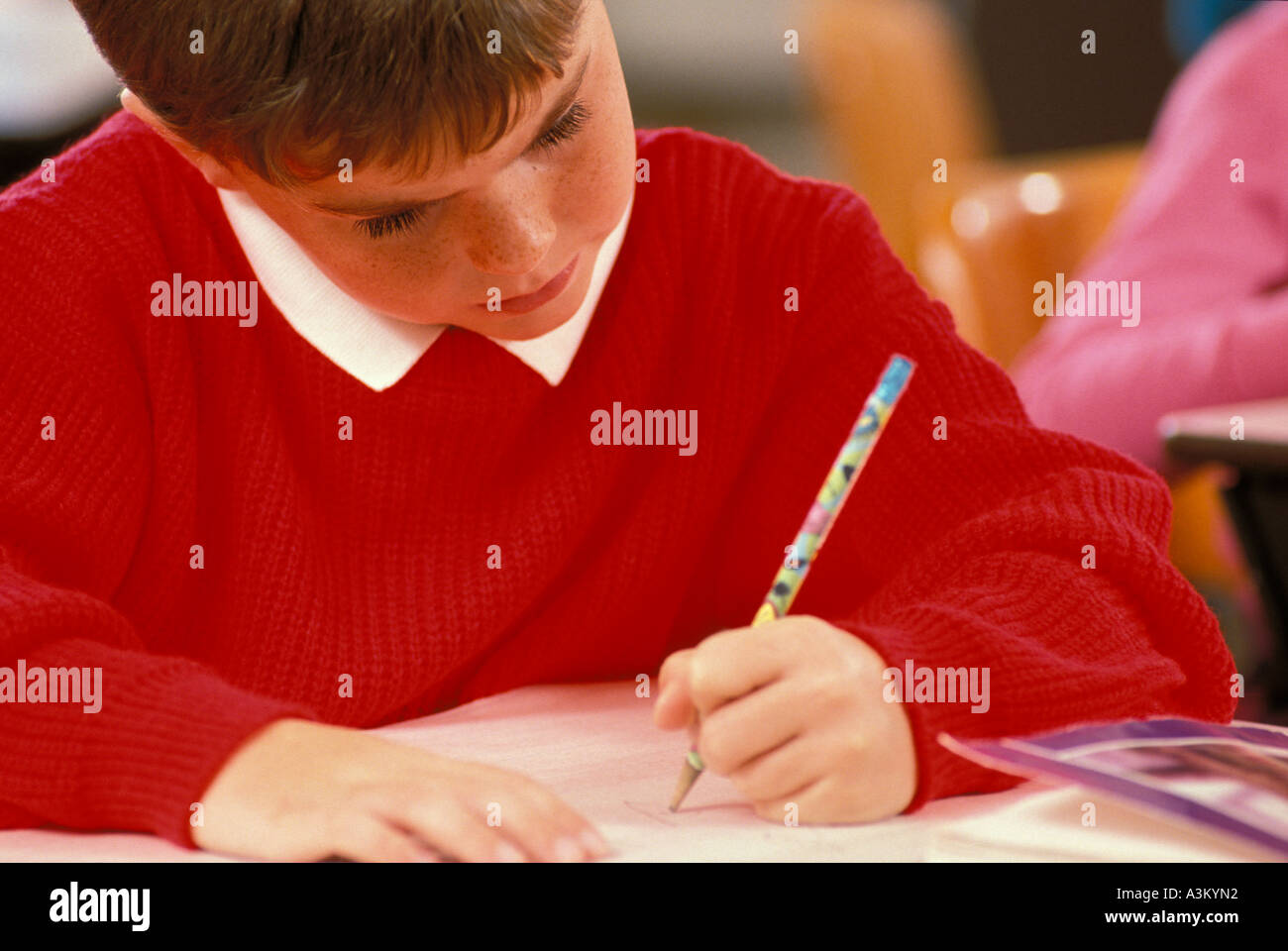 Caucasian male student writing in elementary school class Stock Photo