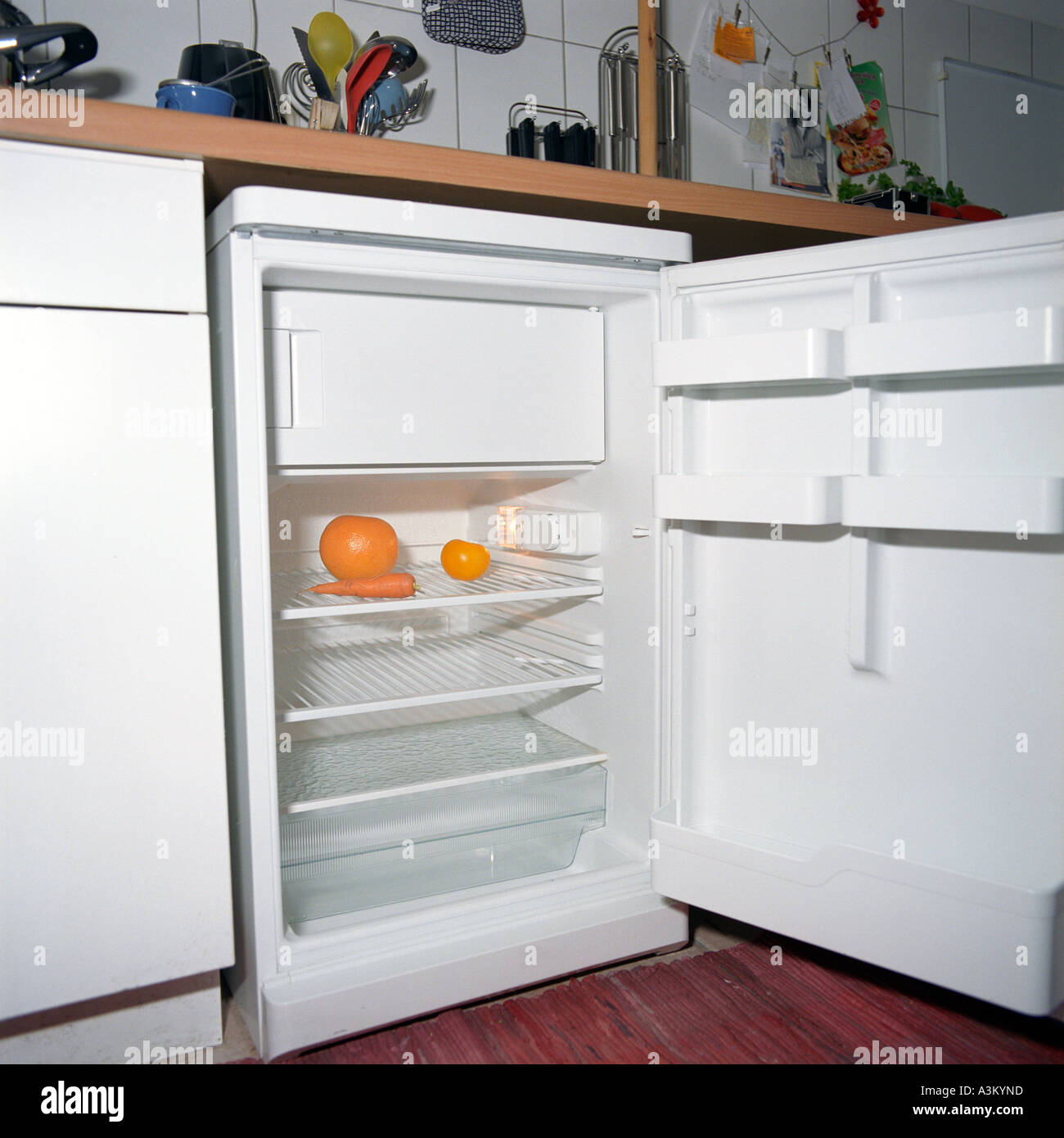 view into an empty fridge in kitchen containing only some orange fruit and vegetables Stock Photo