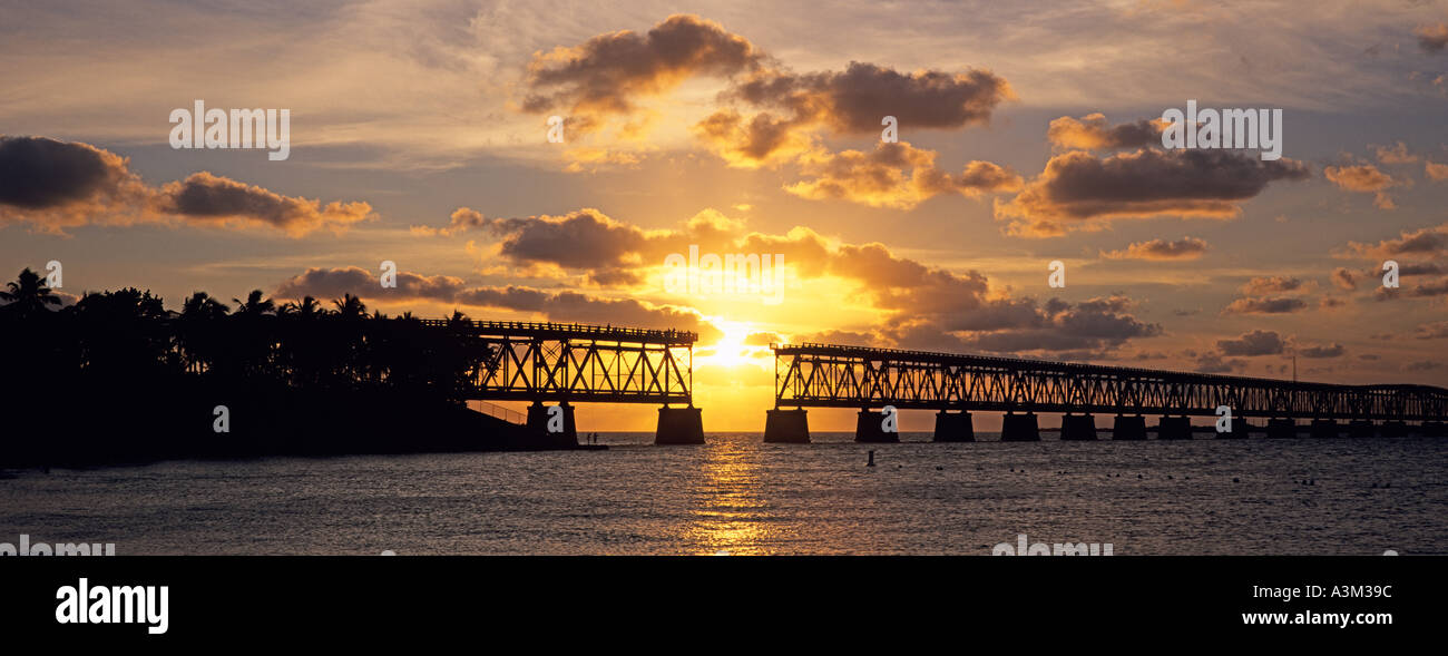 Sun sinks toward Atlantic Ocean framed by historic and abandoned rail road bridge at Bahia Honda State Park the Florida Keys Fl Stock Photo