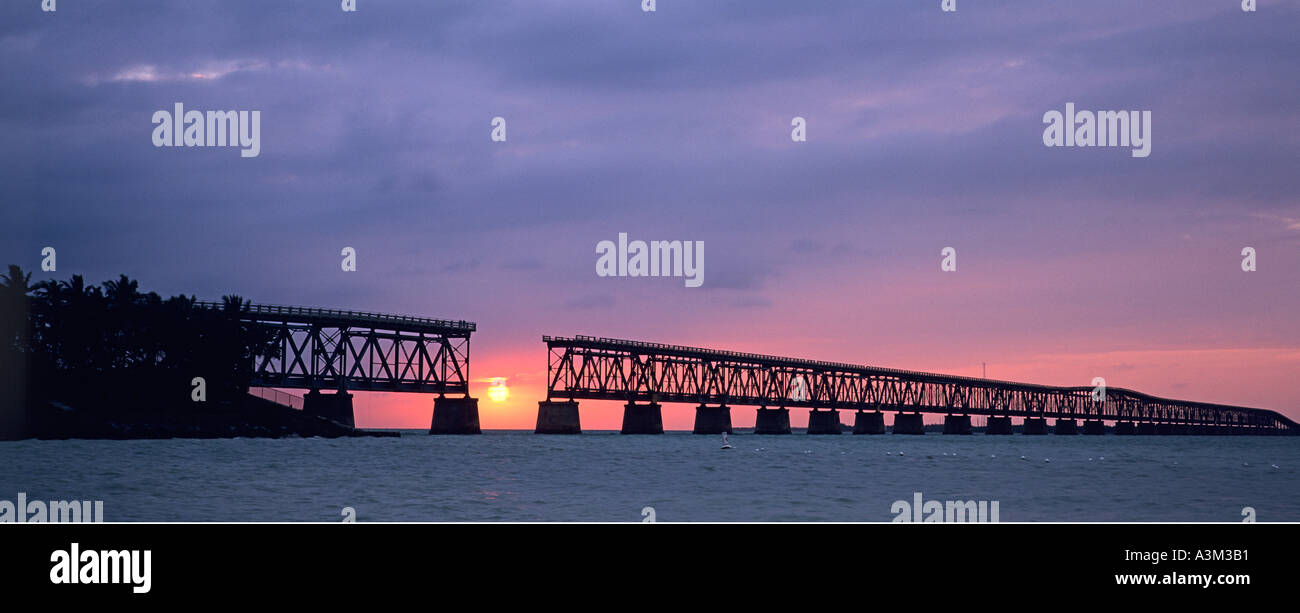 Sun sinks toward Atlantic Ocean framed by historic and abandoned rail road bridge at Bahia Honda State Park the Florida Keys Fl Stock Photo