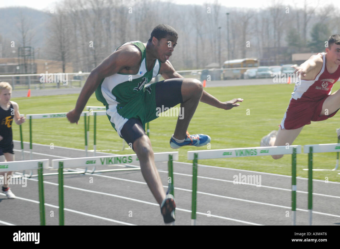 Afro American high school athlete clearing the hurdles at a high school