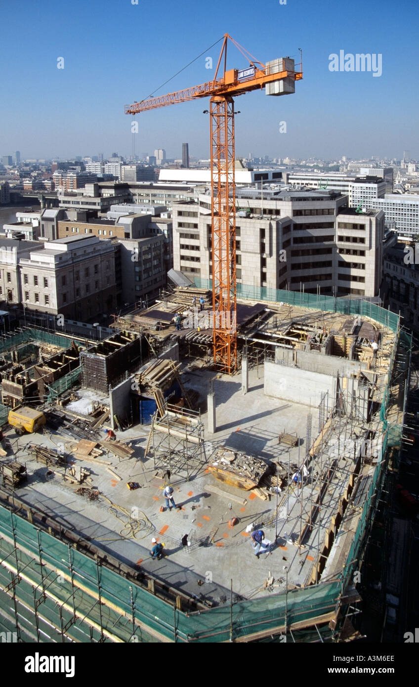Semi aerial looking down on office block construction site with workers tower crane and view towards river Thames and skyline Stock Photo