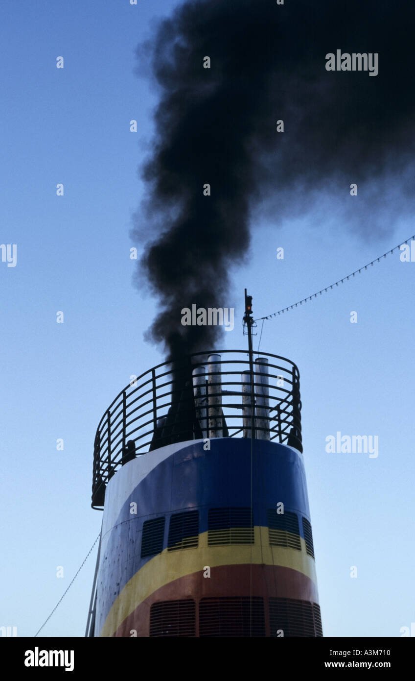 Pollution close up of belching black smoke & soot emissions from ship funnel into air atmosphere damaging the environment & contributes human disease Stock Photo