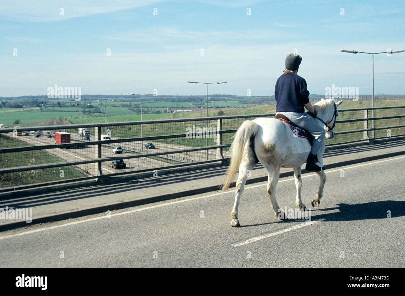 Horse and rider on quiet country lane bridge crossing the M25 motorway Stock Photo