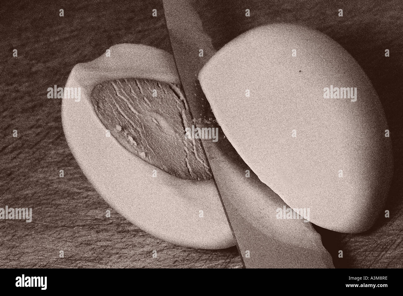 Old black and white image of knife slicing a hard boiled egg on a wooden cutting board Stock Photo