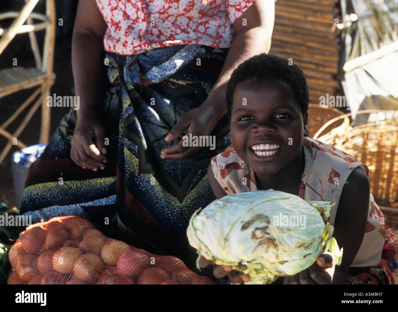 Young black african girl with her mother selling produce in a vegetable market in Beira Mozambique Stock Photo