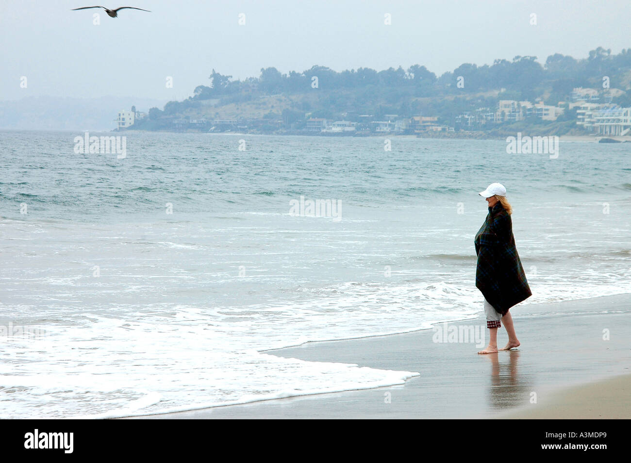 lone woman walking on the beach near Malibu California on a cold foggy