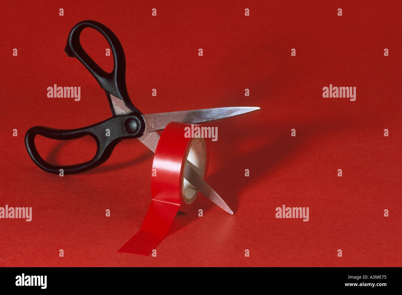 Scissors cutting through red tape Stock Photo