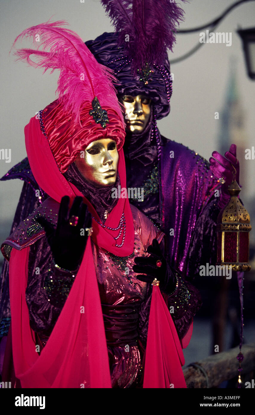 Two people dressed in bright red and purple lavish costumes and masks ...