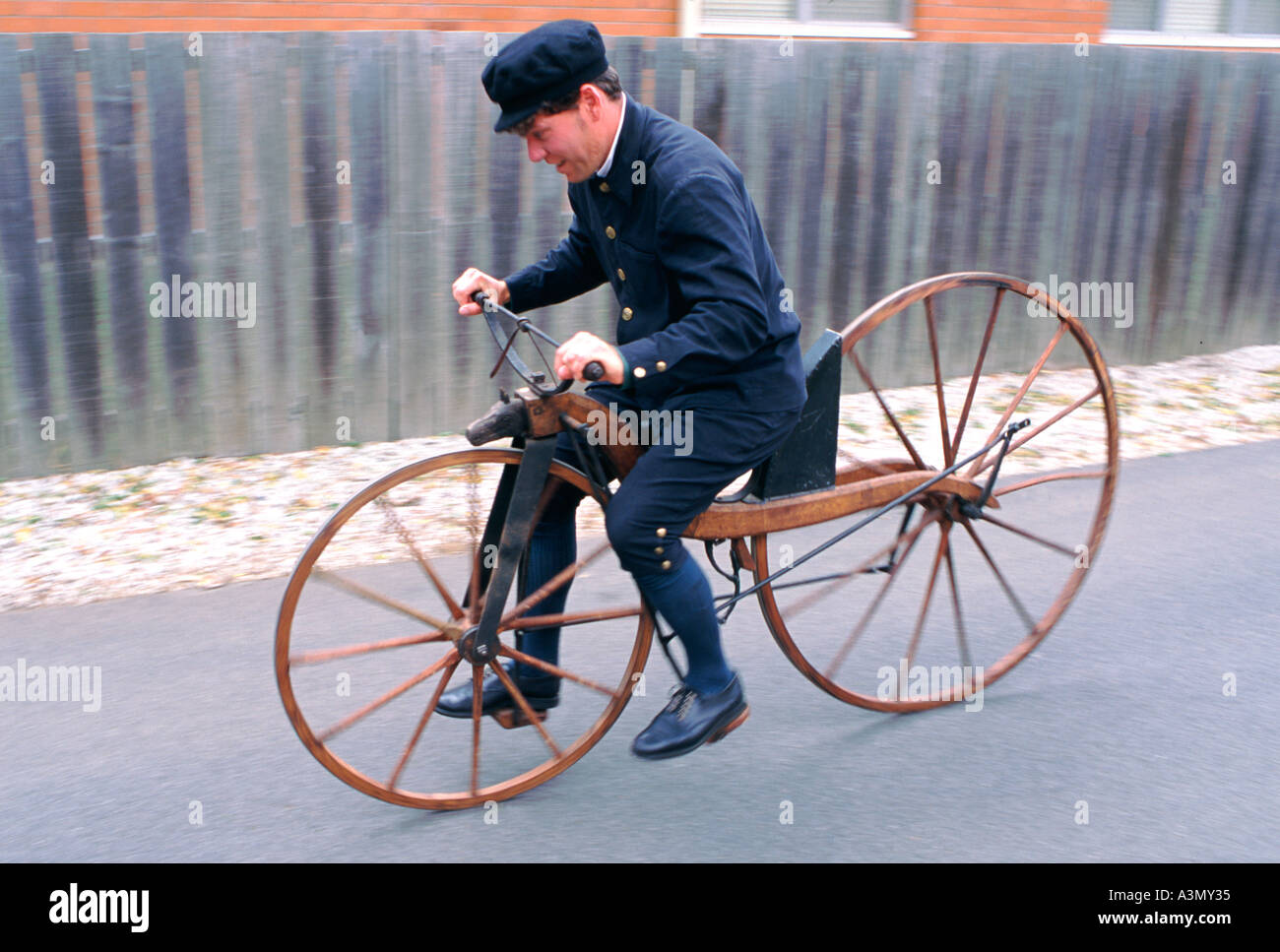 Demonstration of a replica of the first wooden bicycle made by Baron Karl von Drais, by young man wearing cycling costume of the time Stock Photo