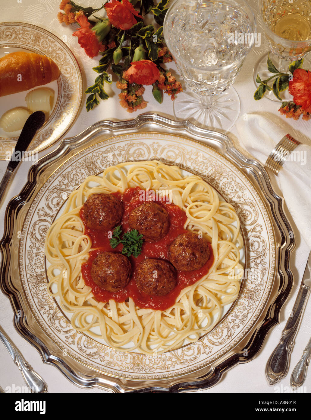 close up elegant dinner plate setting italian pasta spaghetti meat balls  marinara sauce bread rolls butter Stock Photo - Alamy