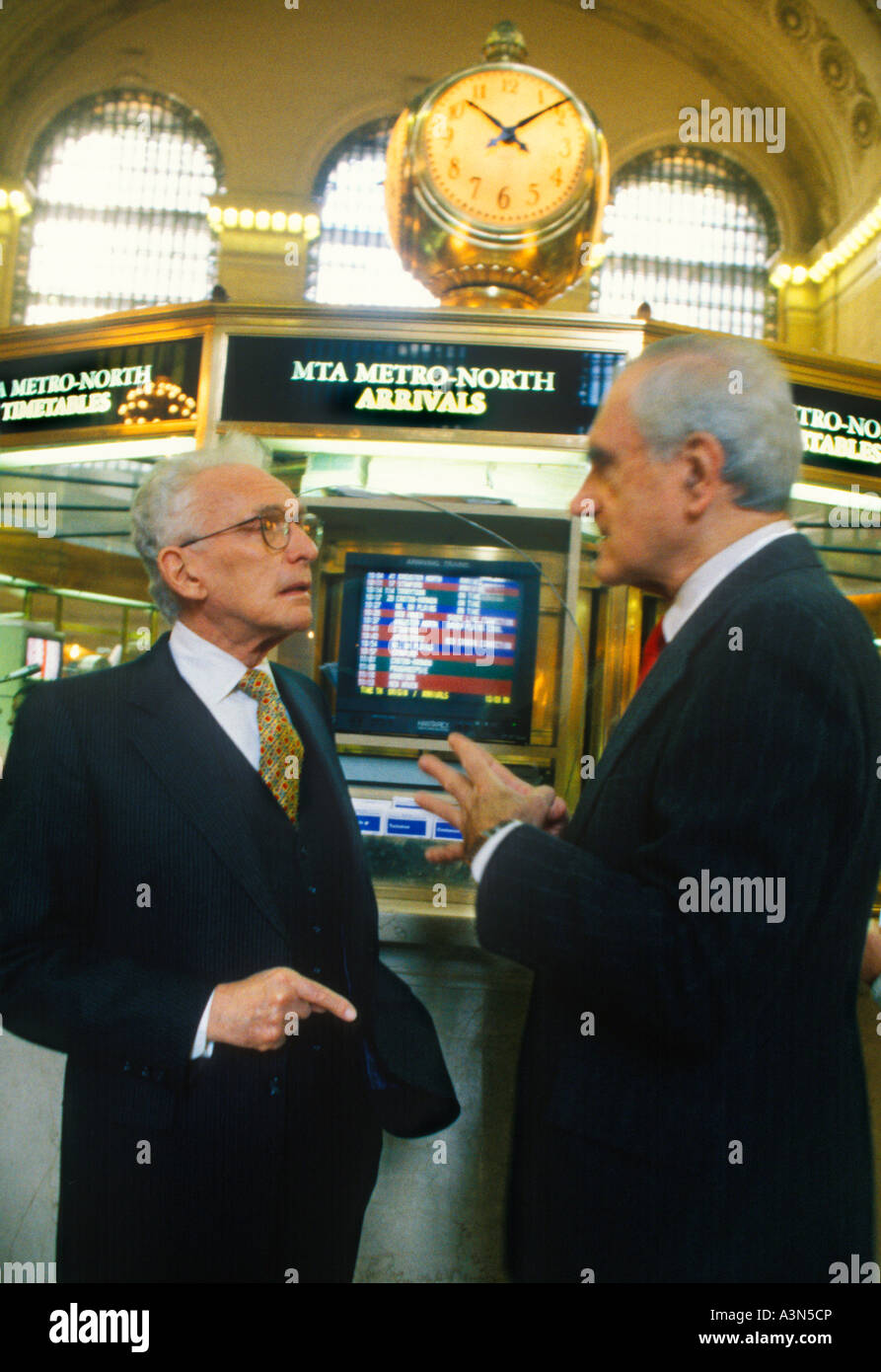 Grand Central Station terminal main concourse New York City. Clock and information booth. Two businessmen talking. Midtown Manhattan USA Stock Photo