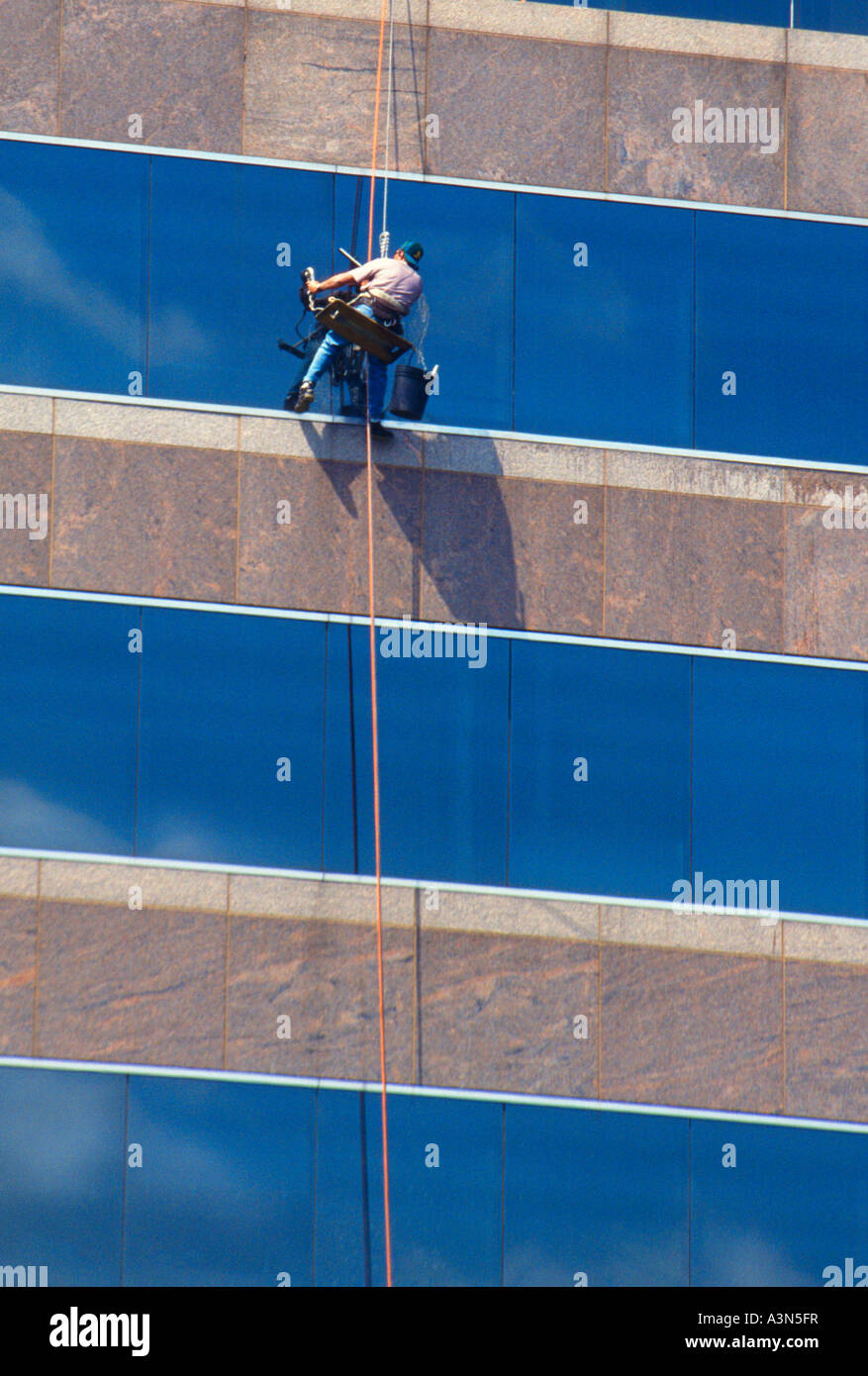 Window Washer Washing Windows On The Outside of a Modern Skyscraper